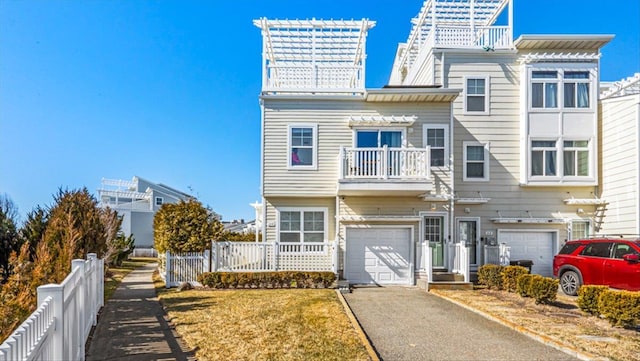 view of front of property with a garage, aphalt driveway, fence, and a balcony