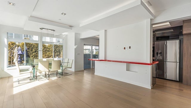 kitchen with stainless steel fridge, baseboards, a kitchen island, wood finished floors, and hanging light fixtures