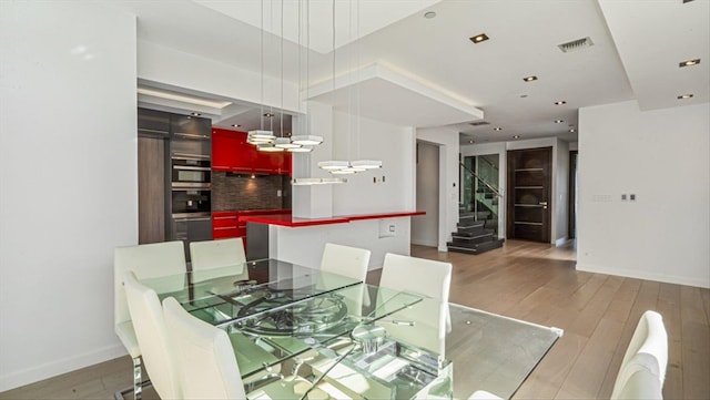 dining room featuring hardwood / wood-style flooring, visible vents, stairway, and baseboards