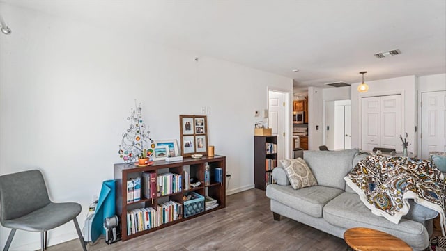 living area with baseboards, visible vents, and wood finished floors