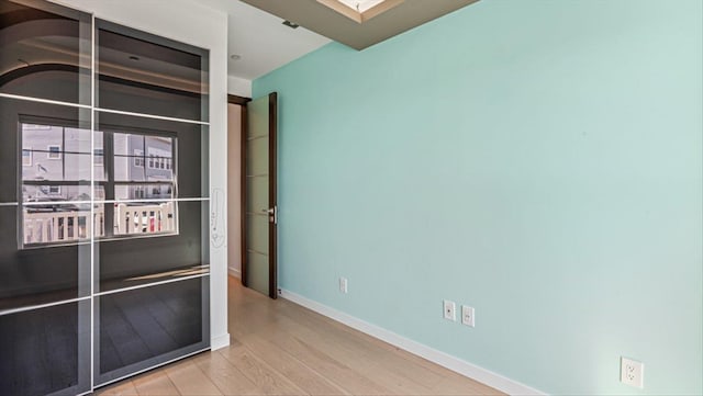 unfurnished room with a skylight, baseboards, and wood finished floors