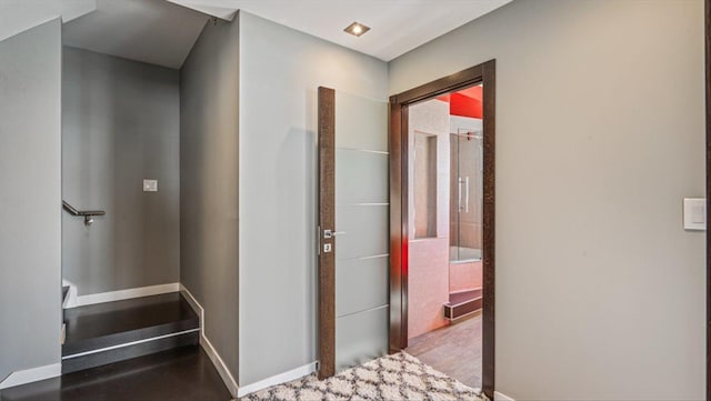 hall featuring stairs, baseboards, and wood finished floors