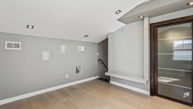 interior space with vaulted ceiling, light wood-style flooring, visible vents, and baseboards