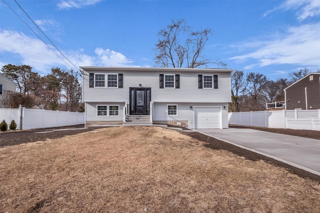 split foyer home featuring entry steps, concrete driveway, fence, and a garage