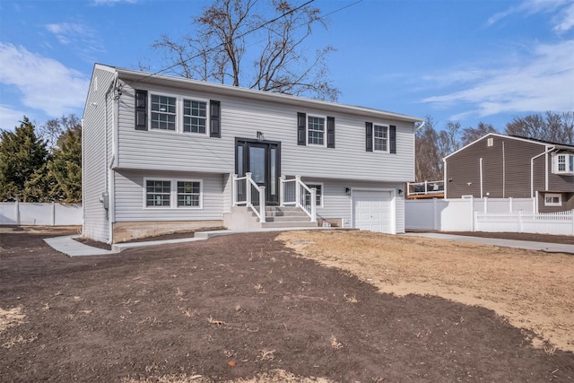 split foyer home with a garage and fence