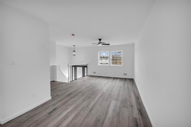 unfurnished living room featuring baseboards, wood finished floors, and a ceiling fan