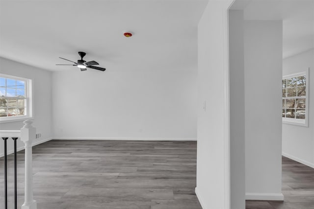 empty room featuring ceiling fan, baseboards, and wood finished floors