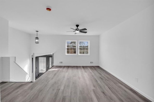 unfurnished living room featuring a ceiling fan, baseboards, and wood finished floors