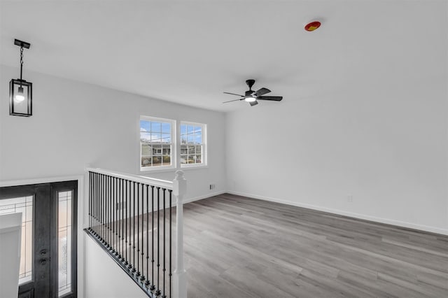 empty room featuring ceiling fan, baseboards, and wood finished floors