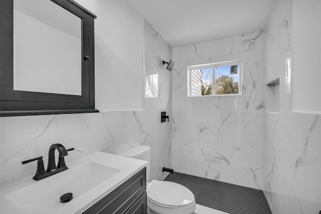 full bath featuring a marble finish shower, toilet, vanity, and tile walls