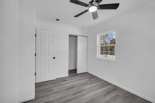 unfurnished bedroom with a closet, baseboards, wood finished floors, and a ceiling fan