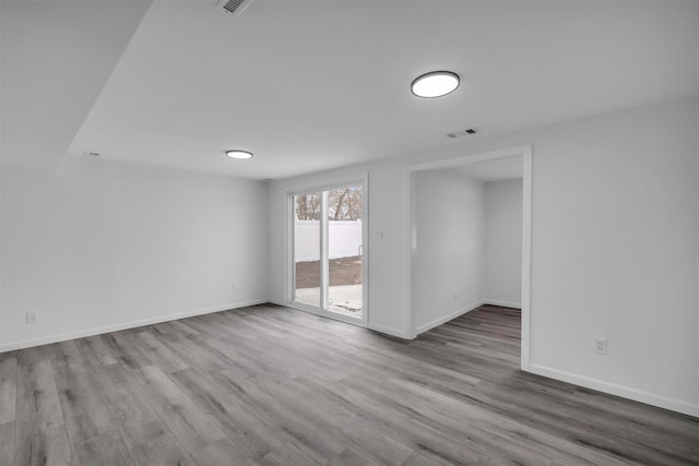 unfurnished room with visible vents, wood finished floors, and baseboards