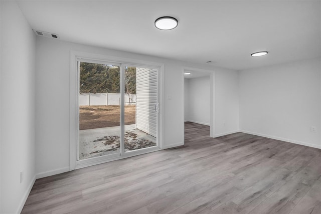 spare room with wood finished floors, visible vents, and baseboards