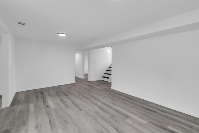 finished basement featuring stairway, baseboards, visible vents, and wood finished floors