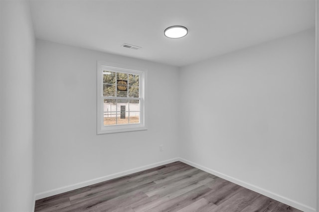 empty room featuring visible vents, baseboards, and wood finished floors