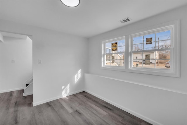 empty room featuring visible vents, baseboards, and wood finished floors