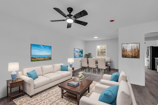 living room with a ceiling fan, baseboards, and wood finished floors