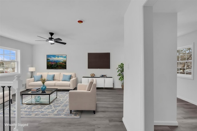 living area featuring ceiling fan, baseboards, and wood finished floors