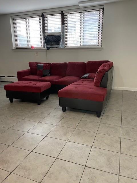 living area featuring light tile patterned floors, baseboards, and a baseboard heating unit