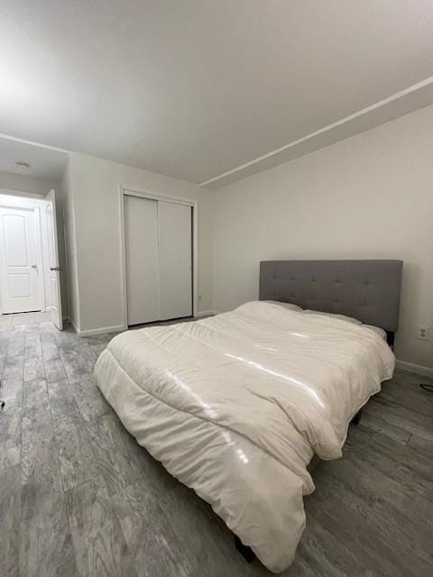 bedroom with baseboards, a closet, and wood finished floors