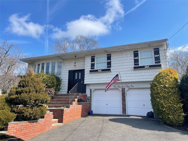 bi-level home featuring aphalt driveway, brick siding, and an attached garage