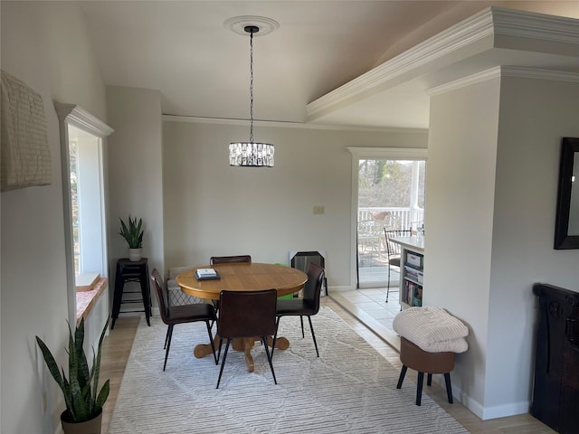 dining area featuring crown molding, light wood-style flooring, and baseboards