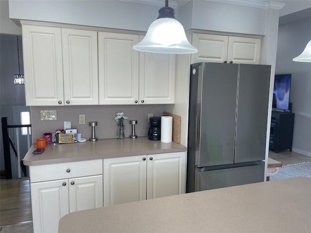 kitchen featuring freestanding refrigerator, light countertops, and white cabinetry