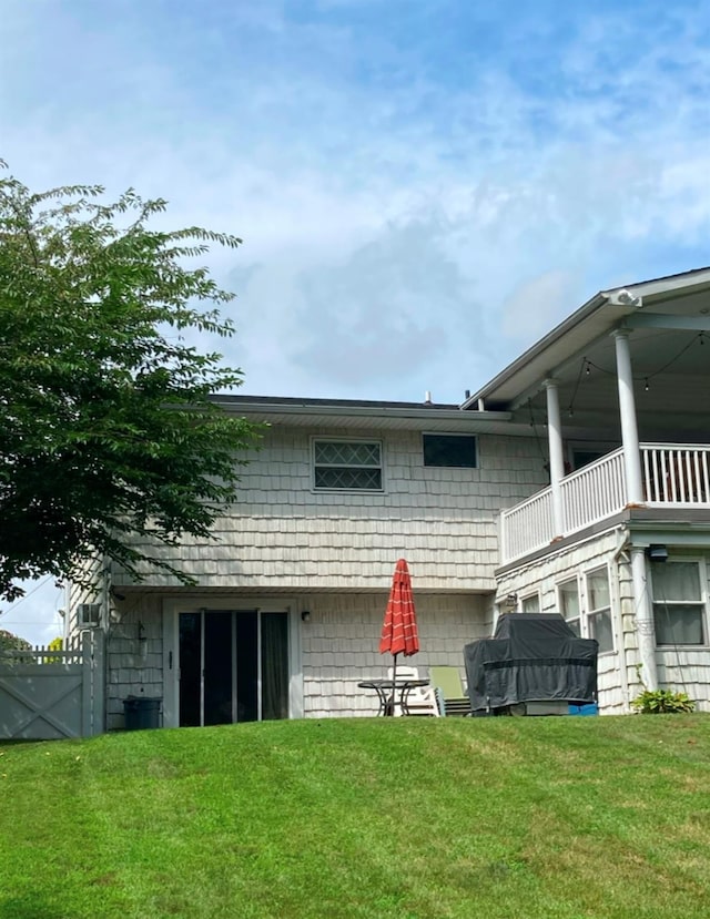 back of house with a balcony and a yard