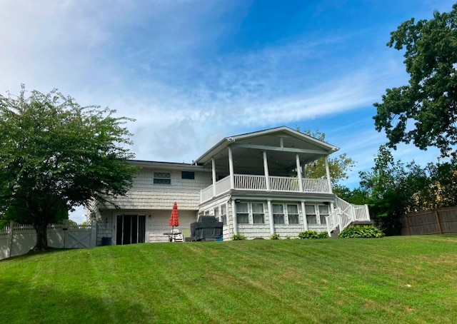 back of house featuring stairway, a lawn, a balcony, and fence