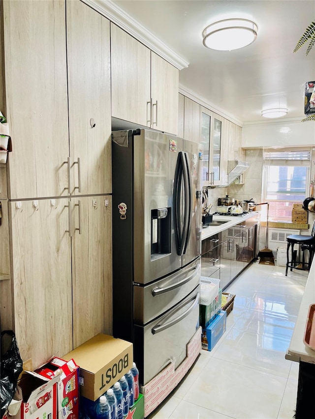 kitchen with stainless steel fridge, visible vents, glass insert cabinets, light countertops, and wall chimney range hood