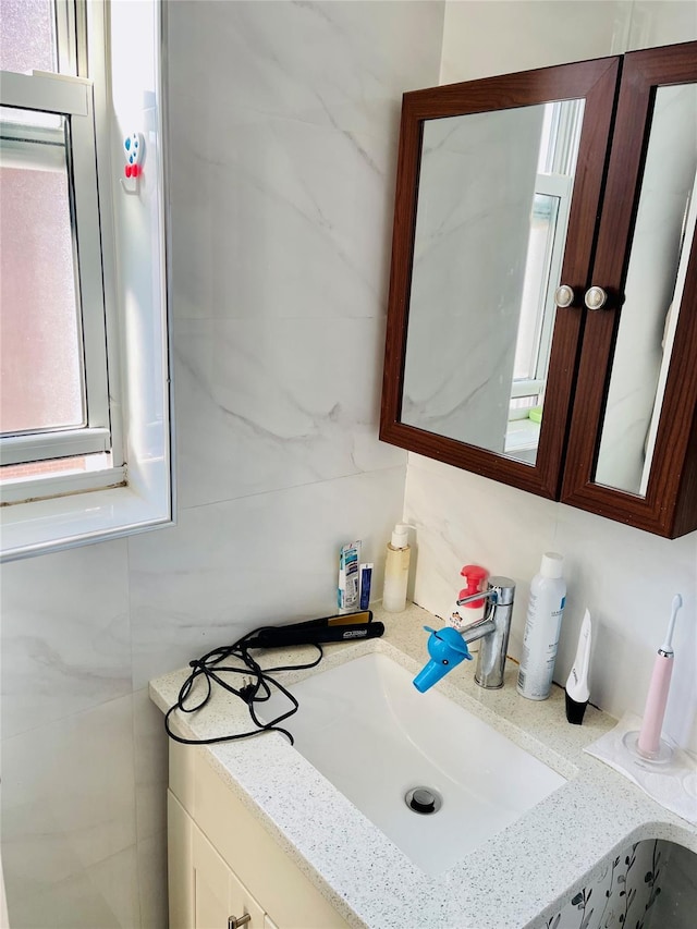 bathroom with vanity and tile walls