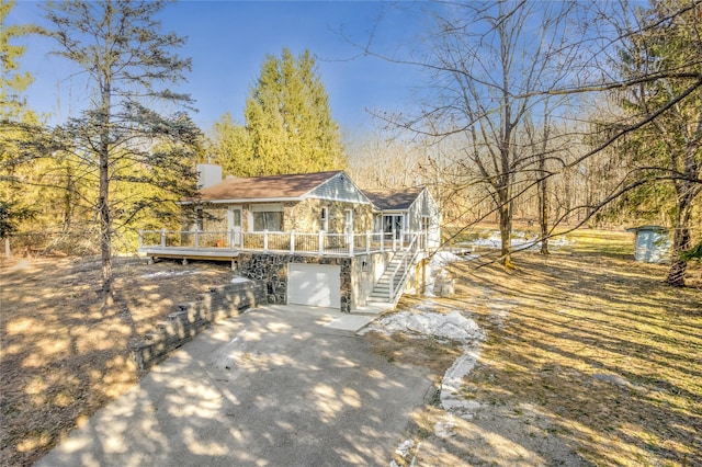 chalet / cabin featuring driveway, stone siding, a chimney, an attached garage, and stairs