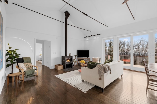 living area featuring a wood stove, beam ceiling, high vaulted ceiling, and hardwood / wood-style floors