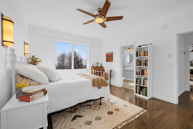 bedroom featuring baseboards, wood-type flooring, ceiling fan, ensuite bathroom, and a sink