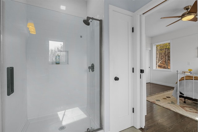 full bathroom featuring a ceiling fan, a stall shower, baseboards, and wood finished floors