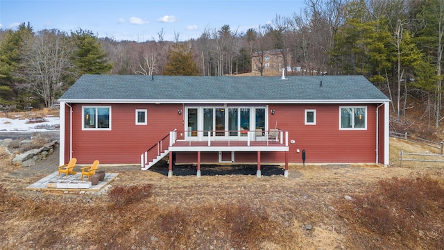 rear view of property with a shingled roof, an outdoor fire pit, a deck, and stairs