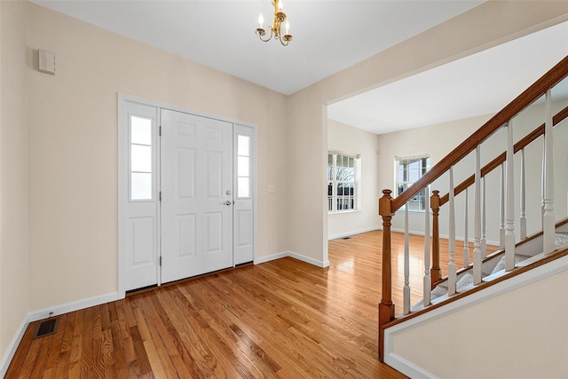 foyer entrance with baseboards, visible vents, stairway, an inviting chandelier, and light wood-type flooring