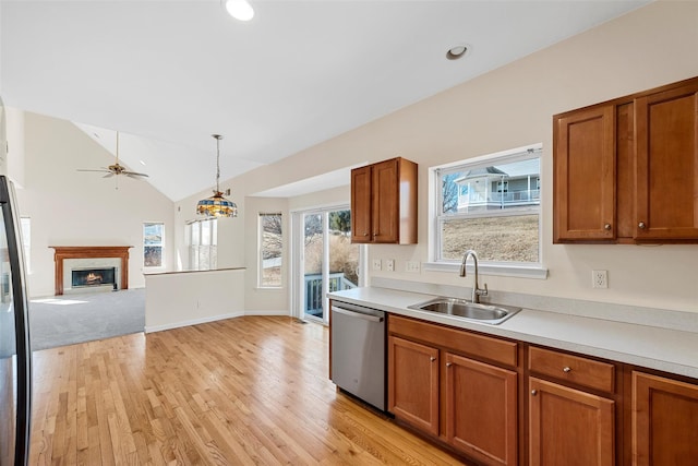 kitchen featuring a sink, a premium fireplace, brown cabinetry, and dishwasher