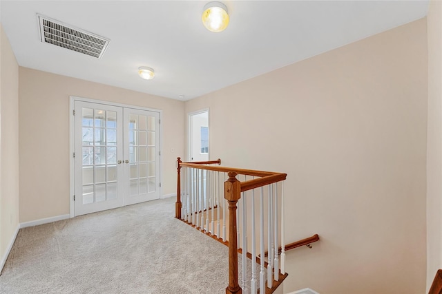 corridor featuring visible vents, baseboards, french doors, carpet, and an upstairs landing