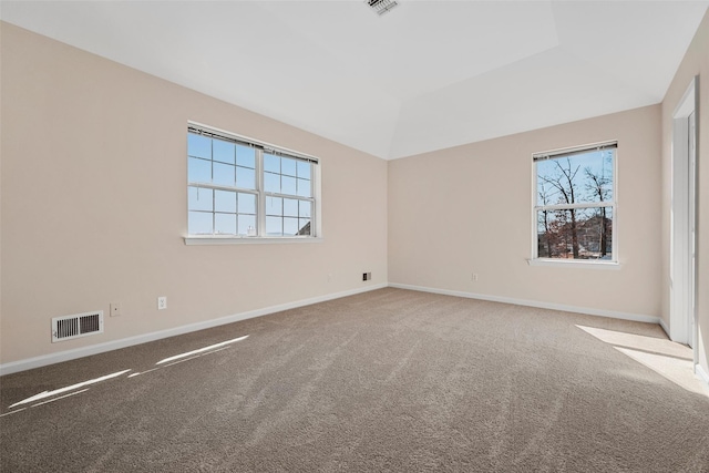 carpeted empty room with baseboards, visible vents, and vaulted ceiling