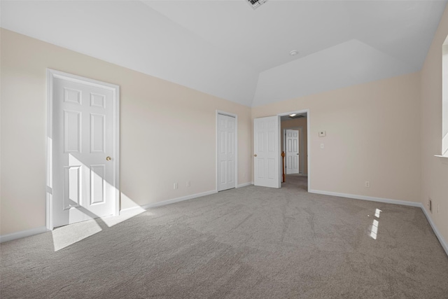 carpeted spare room featuring lofted ceiling, visible vents, and baseboards