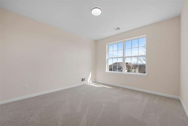 empty room with carpet flooring, visible vents, and baseboards