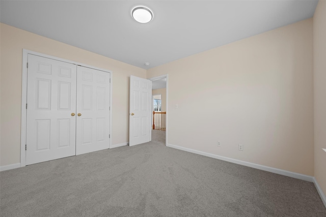 unfurnished bedroom with carpet floors, baseboards, and a closet