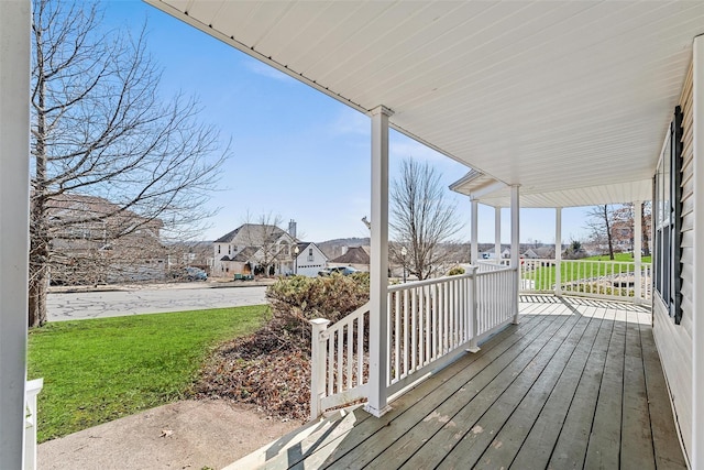 deck featuring covered porch, a residential view, and a yard