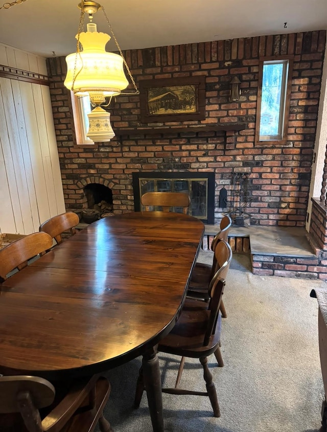 dining room featuring carpet floors, a fireplace, and brick wall