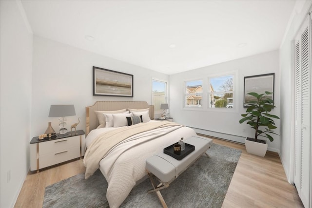 bedroom featuring baseboards, baseboard heating, and light wood-style floors