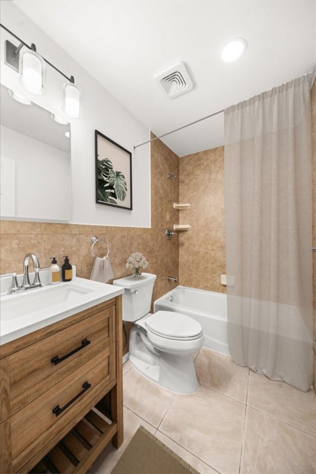 bathroom with visible vents, toilet, shower / bathtub combination with curtain, vanity, and tile walls