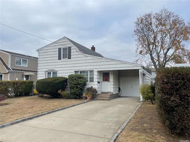 view of front of house with driveway, a chimney, and an attached garage