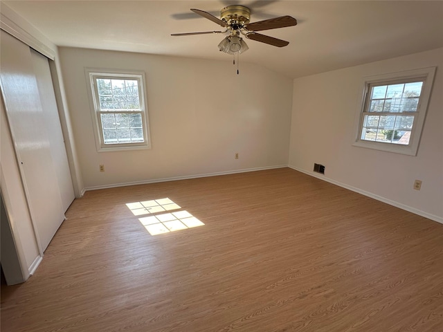 unfurnished room featuring light wood finished floors, baseboards, visible vents, and ceiling fan