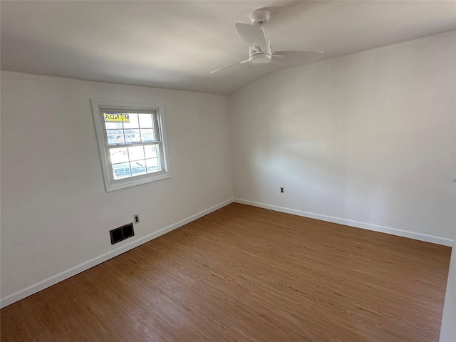 spare room with wood finished floors, visible vents, and baseboards